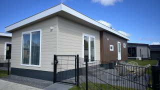 Moderne chalet ved navn Sea bass på Vakantiepark de Zeeuwse Parel i Holland, omgivet af hegn og græs.