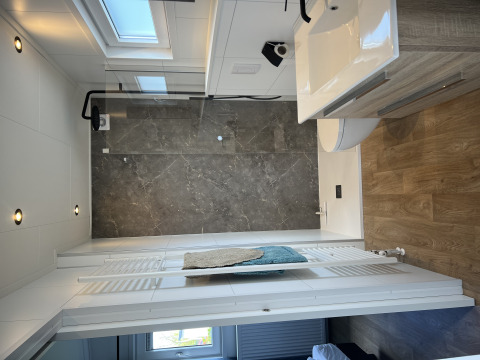 Bagno moderno nel chalet Sea bass a Vakantiepark de Zeeuwse Parel, con doccia e pavimento in legno.