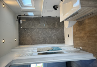 Modernes Badezimmer im Chalet Sea bass, Vakantiepark de Zeeuwse Parel, mit Dusche und Holzfußboden.