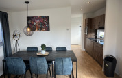 Salle à manger moderne avec chaises bleues et cuisine dans un chalet à Vakantiepark de Zeeuwse Parel, Pays-Bas.