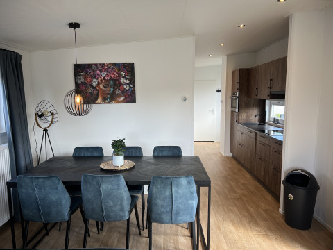 Essbereich und Küche in einem Chalet im Vakantiepark de Zeeuwse Parel mit blauen Stühlen und Kunstwerk.