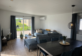Lys stue i chalet Sea bass på Vakantiepark de Zeeuwse Parel, Holland, med moderne møbler og udsigt.