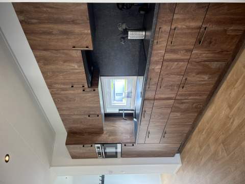 Moderne Küche mit Holzmöbeln und Fenster im Sea bass Chalet, Vakantiepark de Zeeuwse Parel, Niederlande.