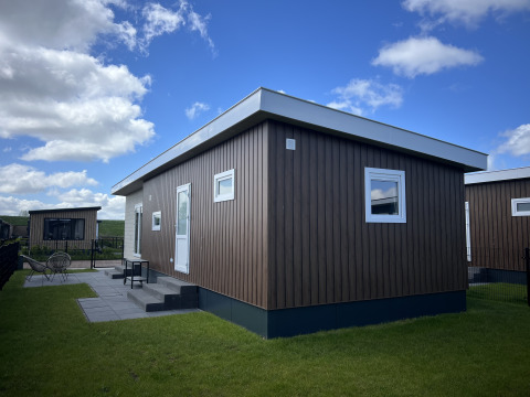 Chalet moderno Sea bass al Vakantiepark de Zeeuwse Parel nei Paesi Bassi con cielo blu e prato verde.