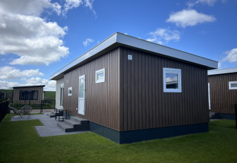 Modern chalet Sea bass bij Vakantiepark de Zeeuwse Parel in Nederland met blauwe lucht en groen gras.