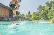 Dreng hopper i poolen med cannonball-spring på Club Les Ormes feriepark, Nouvelle-Aquitaine, Frankrig.