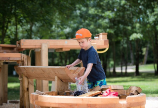 Junge spielt mit Wasserspielplatz im Ferienpark Club Les Ormes, Nouvelle-Aquitaine, Frankreich.