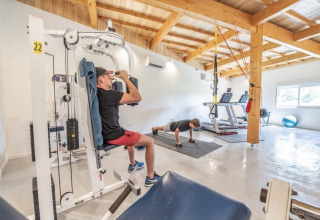 Zwei Personen trainieren in einem hellen Fitnessstudio im Club Les Ormes Ferienpark in Nouvelle-Aquitaine, Frankreich.