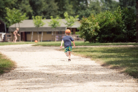Un bambino con cappellino arancione corre su un sentiero ghiaioso al Club Les Ormes, nel Nouvelle-Aquitaine.