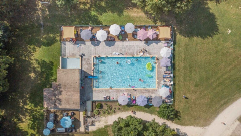 Luftfoto af swimmingpool og solterrasse med parasoller på Club Les Ormes feriepark, Nouvelle-Aquitaine, Frankrig.