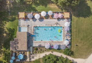Luftfoto af swimmingpool og solterrasse med parasoller på Club Les Ormes feriepark, Nouvelle-Aquitaine, Frankrig.