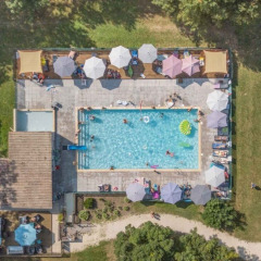 Luftfoto af swimmingpool og solterrasse med parasoller på Club Les Ormes feriepark, Nouvelle-Aquitaine, Frankrig.
