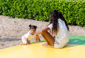 Two children play outdoors on a colorful mat at Berg Lodge - Sauna at Resort Mooi Bemelen in the Netherlands.
