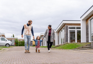 Familie nyder en gåtur foran hytter på Berg Lodge - Sauna i Resort Mooi Bemelen, Holland, overskyet dag.
