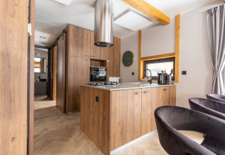 Moderne køkken med træfinish og køkkenø i Panorama Lodge ved Pressegger See, Østrig, med naturligt lys.