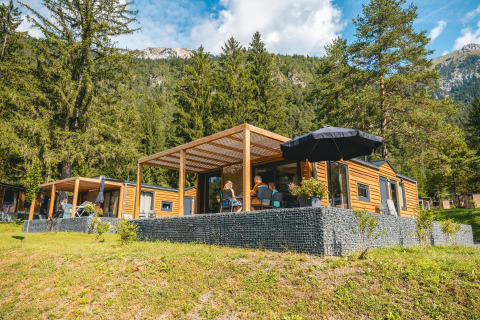 Panorama Lodge en Pressegger See, Austria, rodeada de montañas, árboles y naturaleza exuberante y verde.
