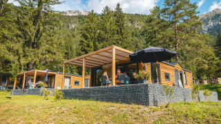 Panorama Lodge en Pressegger See, Austria, rodeada de montañas, árboles y naturaleza exuberante y verde.