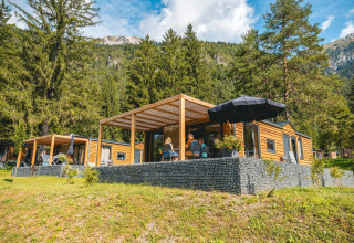 Panorama Lodge en Pressegger See, Austria, rodeada de montañas, árboles y naturaleza exuberante y verde.