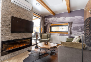 Salon douillet au Panorama Lodge près du lac Pressegger, Autriche, avec cheminée, TV et vue sur la montagne.