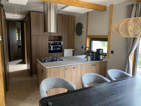 Moderne køkken i Panorama Lodge ved Pressegger See, Østrig, med trækabinetter og spisebord.