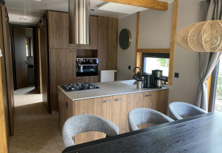 Moderne køkken i Panorama Lodge ved Pressegger See, Østrig, med trækabinetter og spisebord.