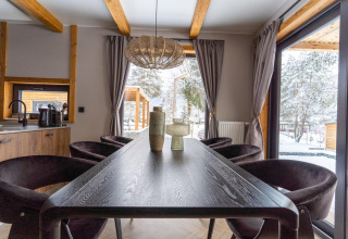 Comedor moderno con vigas de madera, ventanas grandes y vista nevada en Panorama Lodge, Pressegger See.