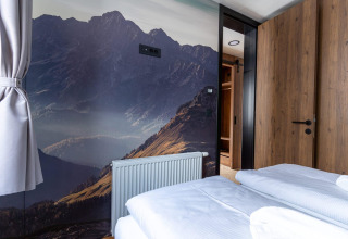 Soveværelse i Panorama Lodge ved Pressegger See, Østrig, med bjergmotiv på væggen og moderne indretning.