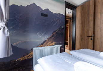 Chambre de la Panorama Lodge au Pressegger See, Autriche, avec fresque de montagne et décor moderne.
