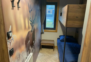 Acogedora habitación pequeña en Panorama Lodge en Pressegger See, Austria, con literas y mural de ciervo.