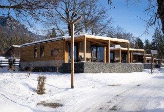 Cabañas de Panorama Lodge en un paisaje nevado de invierno, con montañas al fondo y cielo azul claro.
