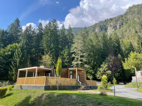 Cabaña de madera en Panorama Lodge, Pressegger See, Austria, rodeada de bosque y montañas en un día soleado.