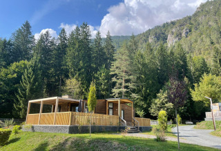 Cabaña de madera en Panorama Lodge, Pressegger See, Austria, rodeada de bosque y montañas en un día soleado.