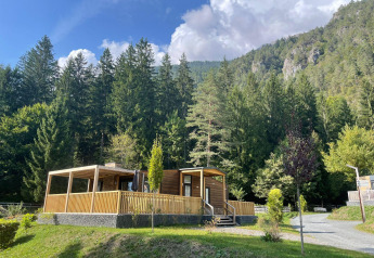 Cabaña de madera en Panorama Lodge, Pressegger See, Austria, rodeada de bosque y montañas en un día soleado.