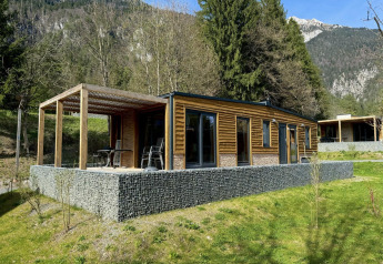 Panorama Lodge at Pressegger See in Austria, modern wooden lodge with patio, surrounded by scenic mountains.