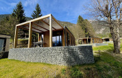 Moderne Panorama Lodge ved Pressegger See i Østrig, med træterrasse og smuk bjergudsigt i baggrunden.