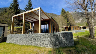 Moderne Panorama Lodge am Pressegger See in Österreich mit Holzterrasse und Bergblick im Hintergrund.