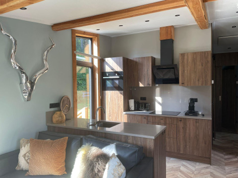 Moderna cocina y sala de estar en Panorama Lodge en Pressegger See, Austria, con detalles de madera y ventanal.