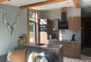 Moderna cocina y sala de estar en Panorama Lodge en Pressegger See, Austria, con detalles de madera y ventanal.