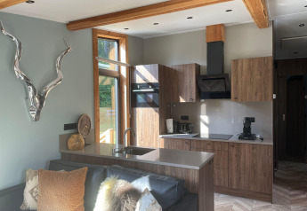 Moderna cocina y sala de estar en Panorama Lodge en Pressegger See, Austria, con detalles de madera y ventanal.