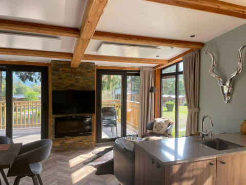 Salon lumineux à Panorama Lodge au Pressegger See en Autriche, avec de grandes fenêtres et une décoration moderne.