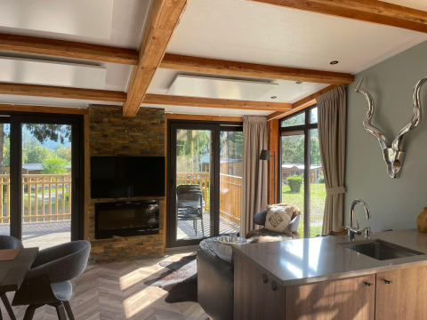 Helles Wohnzimmer in der Panorama Lodge am Pressegger See in Österreich mit großen Fenstern und moderner Einrichtung.