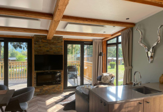 Zona de estar luminosa en Panorama Lodge en Pressegger See, Austria, con grandes ventanales y decoración moderna.