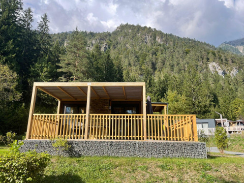 Panorama Lodge en Pressegger See, Austria, cabaña de madera con terrazas y montañas boscosas al fondo.