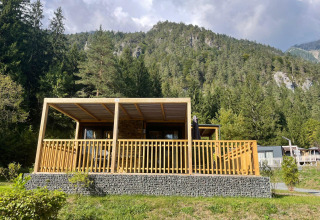 Panorama Lodge en Pressegger See, Austria, cabaña de madera con terrazas y montañas boscosas al fondo.