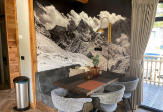 Coin repas à la Panorama Lodge au Pressegger See en Autriche, avec fresque murale de montagne et déco chaleureuse.