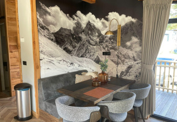 Zona pranzo alla Panorama Lodge presso il Pressegger See in Austria con murale di montagna e arredi moderni.