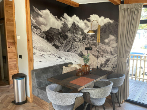 Dining area at Panorama Lodge by Pressegger See in Austria, featuring a mountain mural and cozy decor.