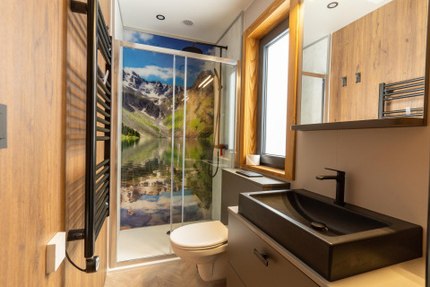 Moderne badkamer in de Panorama Lodge bij Pressegger See, Oostenrijk, met douchewand met berglandschap.