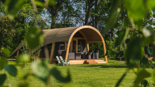 Tienda safari Tent lodge XL + sanitario en Holiday Resort 't Schuttenbelt, Países Bajos, rodeada de naturaleza verde.