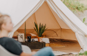 Indvendig udsigt til Bell Tent 500 hos REBL Outdoor i Holland med hyggelig indretning og plante.